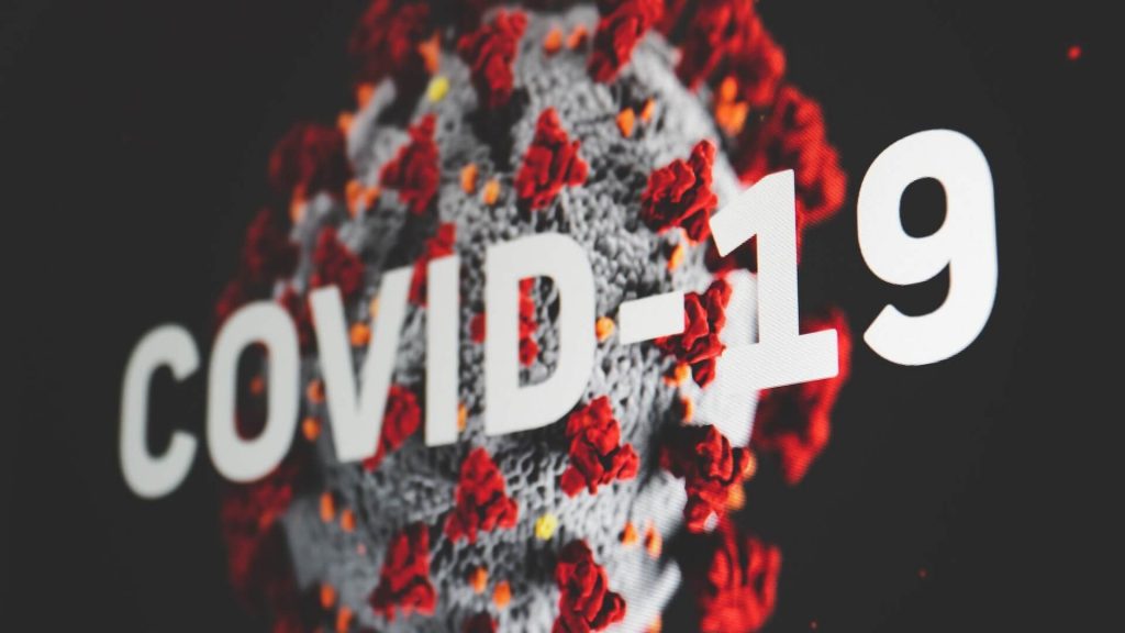 A visual representation of the Covid-19 virus with the words 'Covid-19' above it.